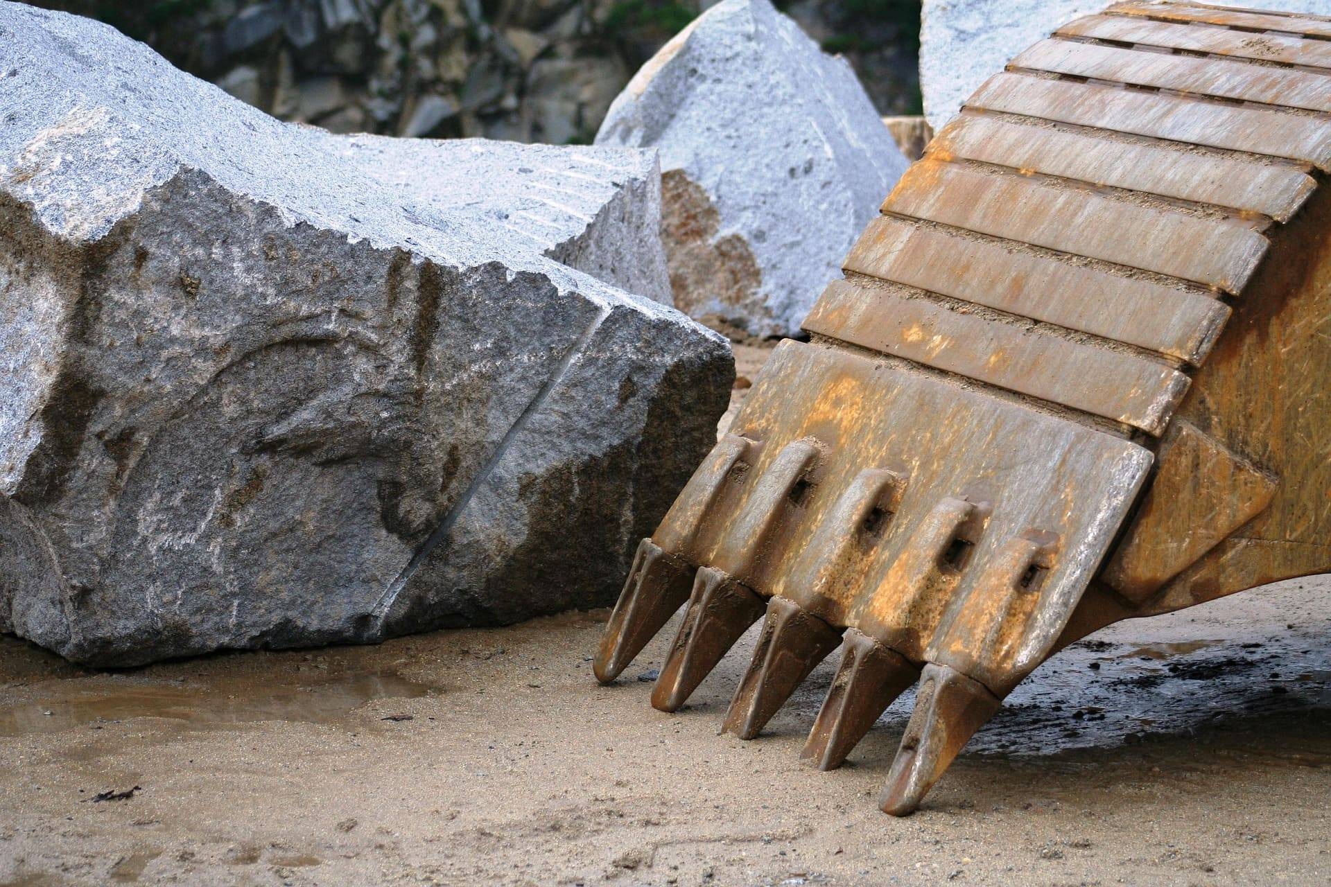 Excavator bucket teeth against granite ore in a quarry